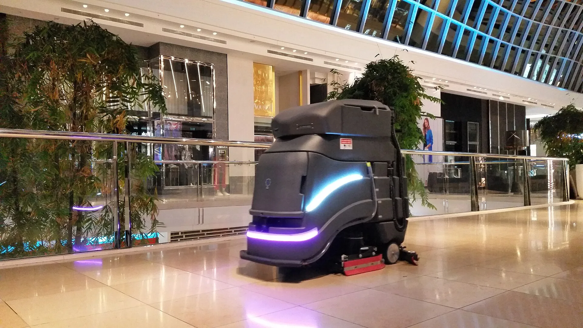 An autonomous floor scrubber working a polished concourse floor